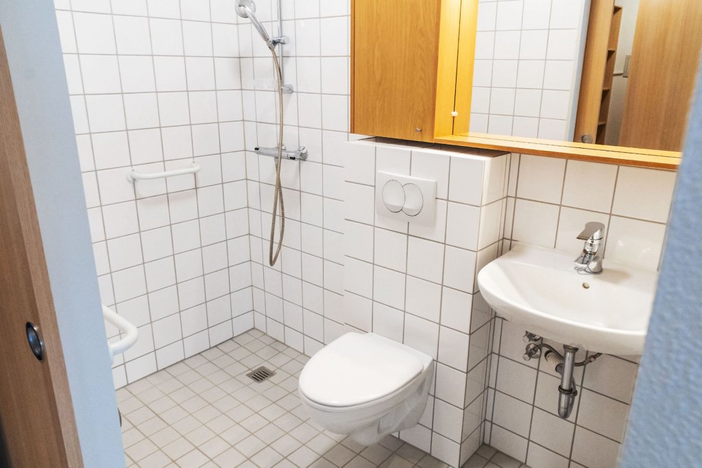 Lítið baðherbergi, flísalagt með litlum hvítum flísum
