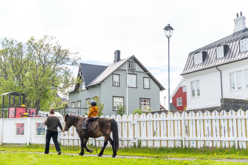 Barn á hestbaki og fullorðnir í kring.