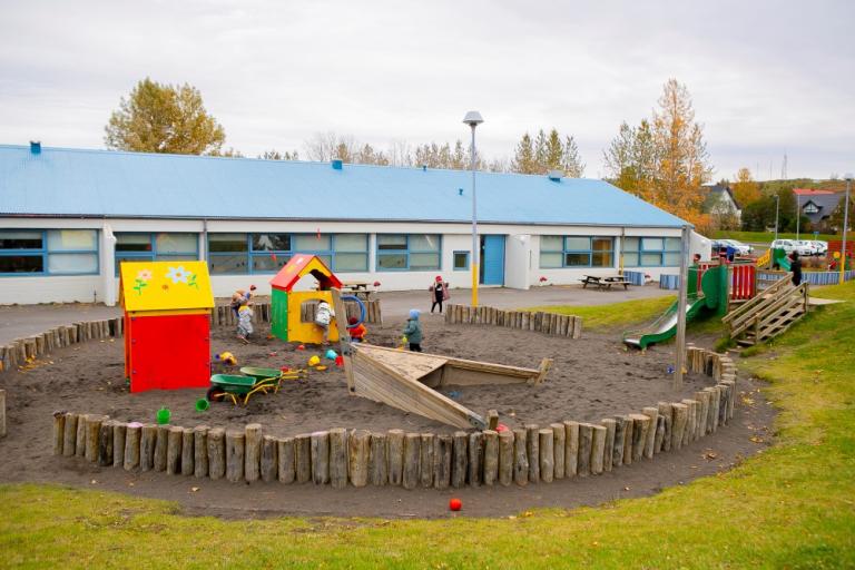 Sandkassi og leiktæki á lóð Jöklaborgar.