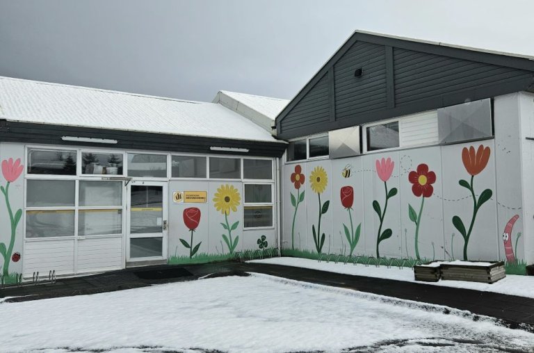 White house with painted flowers, home to the Regnboginn after-school program. 