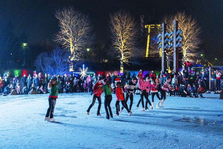 A figure skating group from Reykjavík Skating Club performed on the ice at the opening of Christmas Valley 2024. Darkness, Christmas-decorated tree in the background