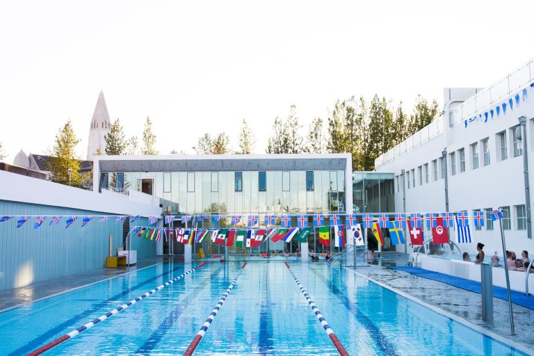 Sundhöll Reykjavíkur's outdoor pool. An empty pool with Icelandic flags and international flags hanging above it.