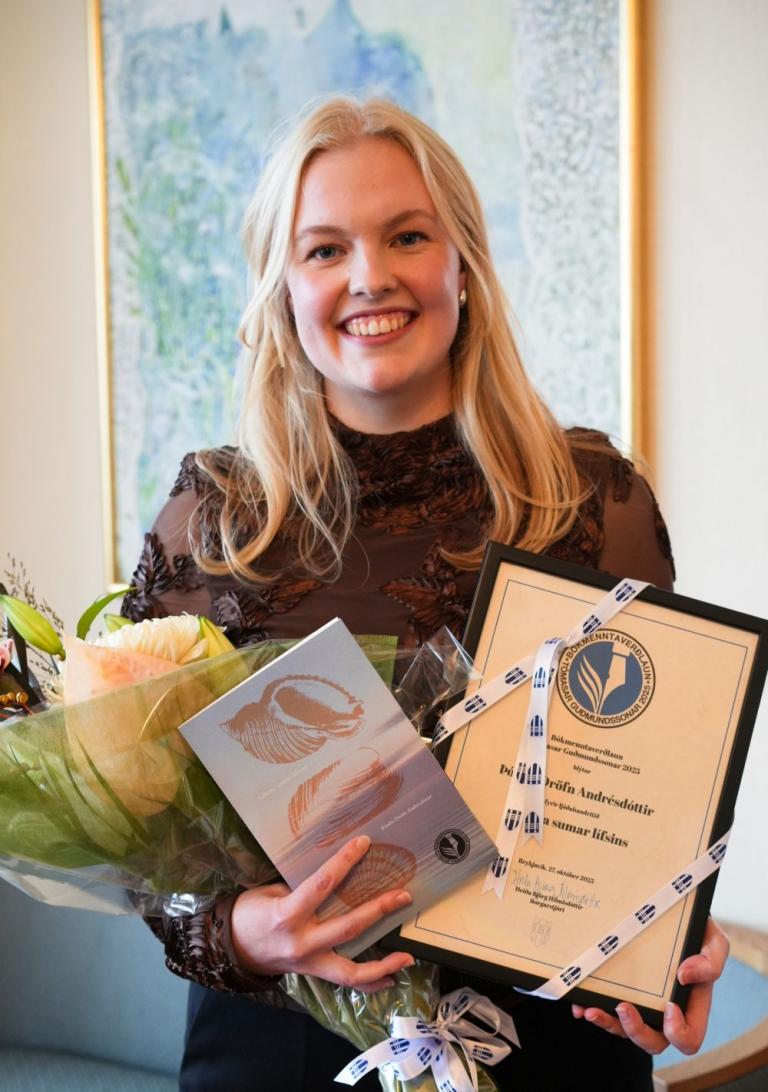Þórdis Dröfn Andrésdóttir með blóm og verðlaunaskjal