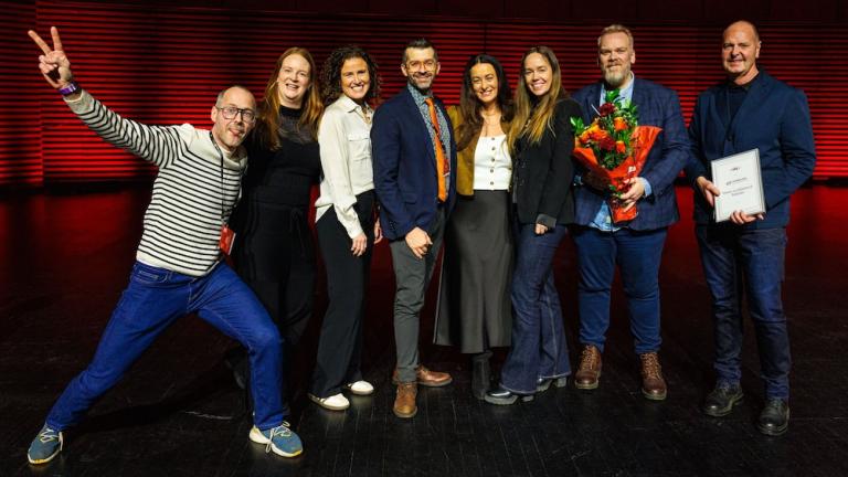 People standing in a line holding flowers and awards.