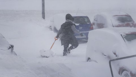 Kona að brjótast í gegnum skafl með skóflu í hendi.