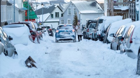 Smábíll er ekið niður götu í miðbæ Reykjavíkur í miklum snjó.