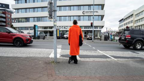 A pedestrian waits at a traffic light near Hlemmur.