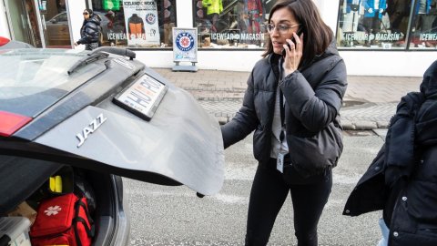 Sara talar í síma við bíl VoR-teymisins.