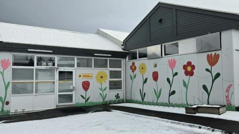 White house with painted flowers, home to the Regnboginn after-school program. 