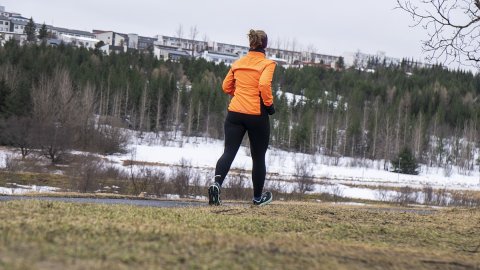 Kona að hlaupa úti. Skógur og snjór.