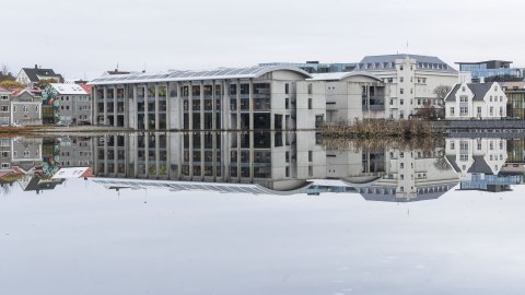 Ráðhús og húsin í kring speglast í spegilsléttri Tjörninni