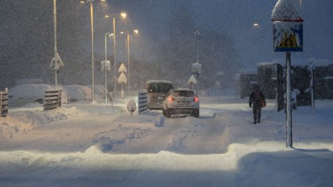 Bíl á götu með miklum snjó og ein manneskja á gangi