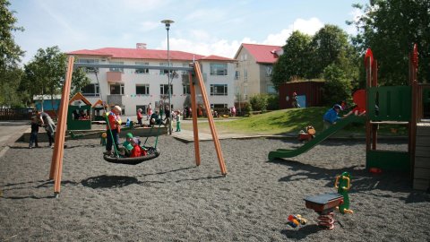 Krakkar að róla á leikskólalóð.